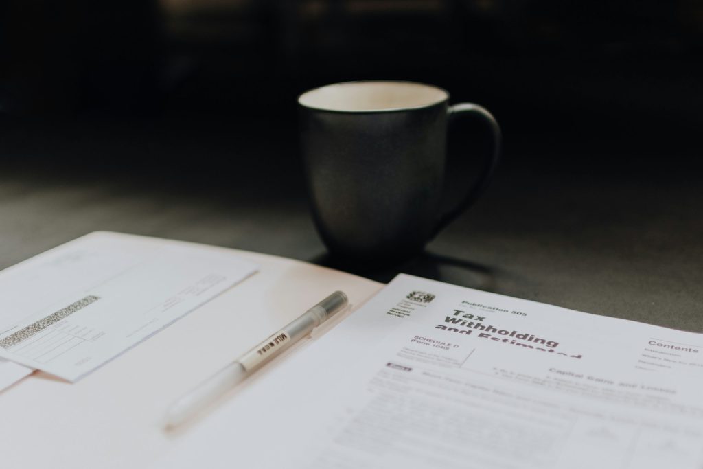 IRS tax withholding and estimated tax publication next to a pen and coffee mug on a desk