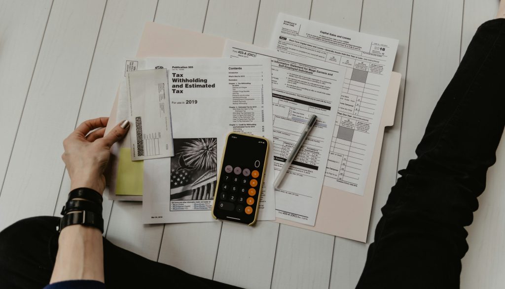 Person reviewing small business tax deduction documents with a calculator and phone on a desk