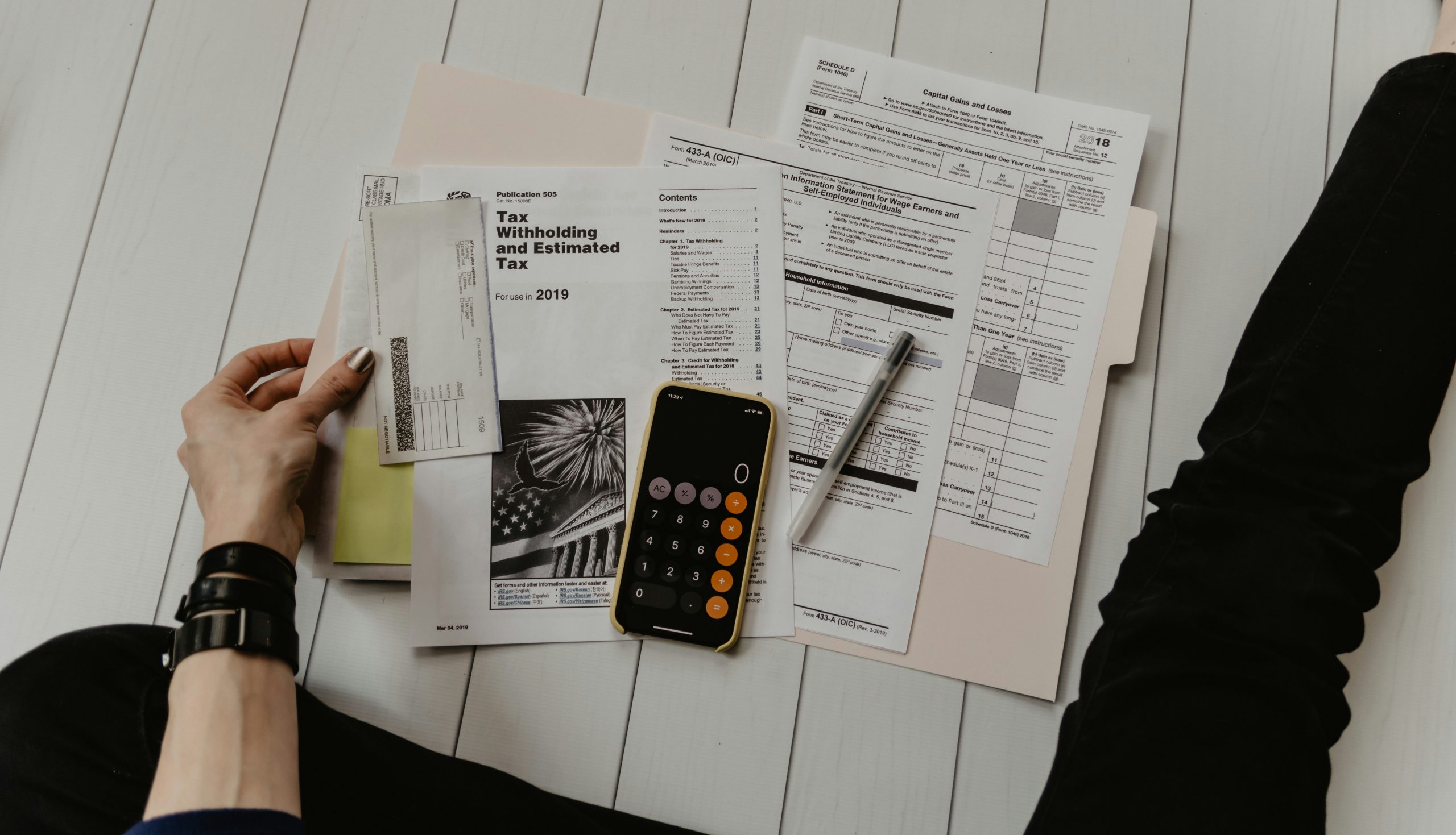 Person reviewing small business tax deduction documents with a calculator and phone on a desk