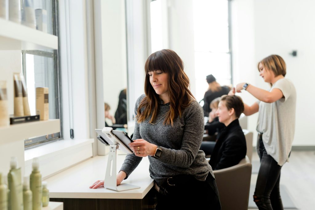A small business owner reviewing financials on a tablet at the front desk of her salon
